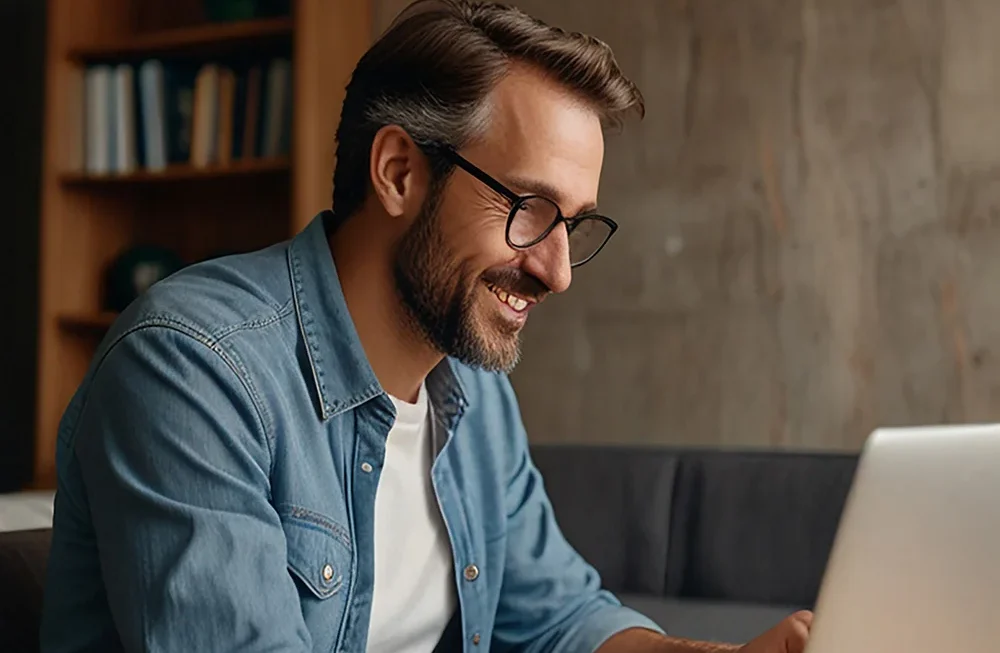 Smiling professional working on a laptop while reviewing marketing strategy